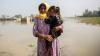 A woman holding her daughter with flood in the background